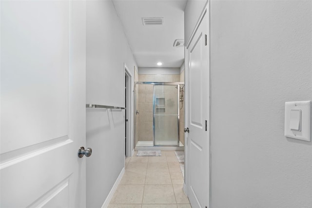 hallway featuring light tile patterned floors, baseboards, and visible vents