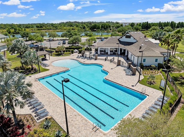 community pool featuring a patio, a water view, and fence