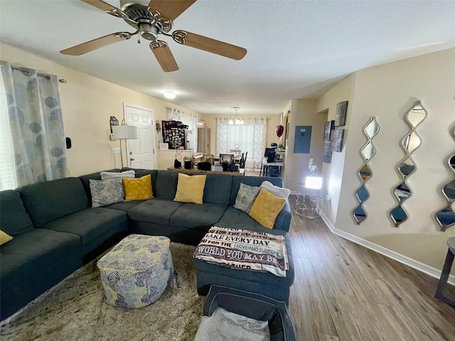 living area with ceiling fan with notable chandelier, baseboards, and wood finished floors