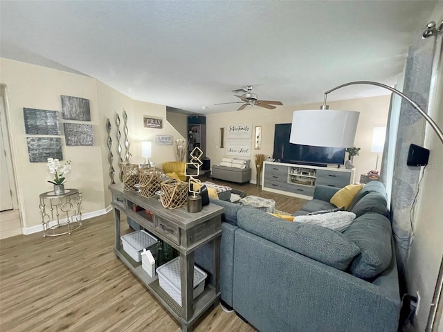 living room featuring wood finished floors, a ceiling fan, and baseboards