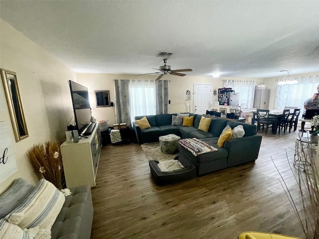 living room featuring plenty of natural light, a textured ceiling, visible vents, and dark wood-type flooring