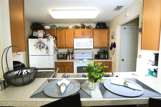 kitchen with light countertops, white appliances, brown cabinetry, and visible vents