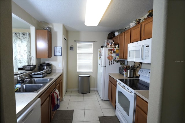 kitchen with brown cabinetry, white appliances, light countertops, and a sink