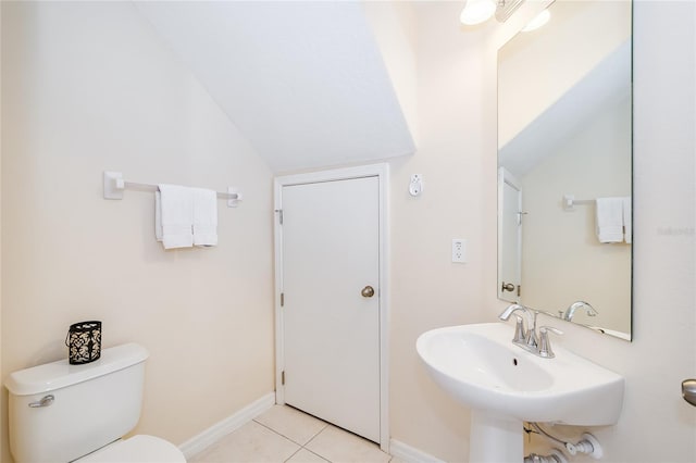 half bathroom featuring baseboards, toilet, lofted ceiling, tile patterned flooring, and a sink