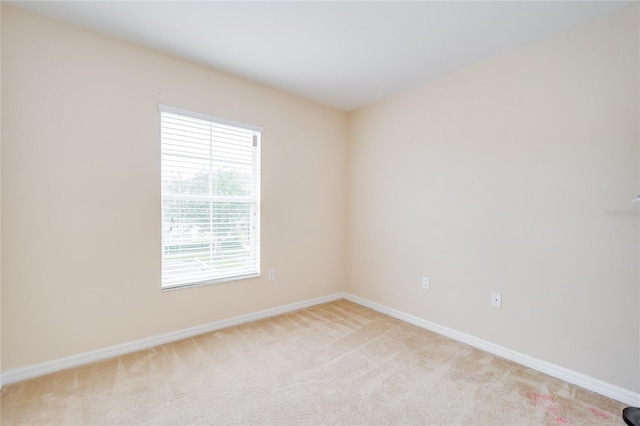 empty room featuring light colored carpet and baseboards