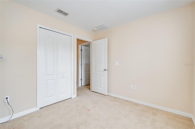 unfurnished bedroom with light carpet, baseboards, visible vents, and a closet