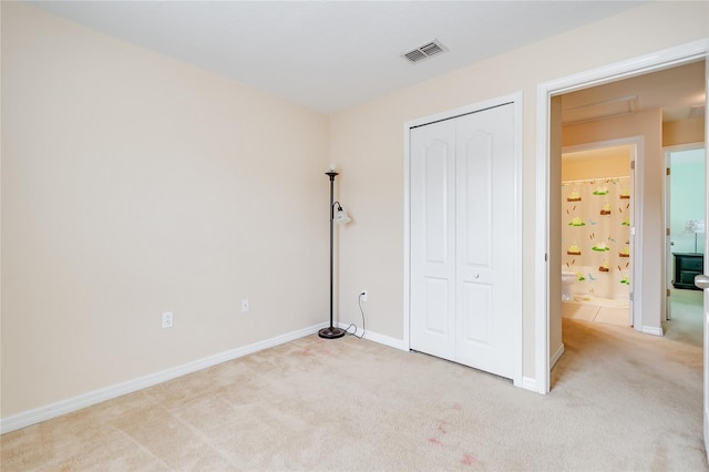 unfurnished bedroom with a closet, visible vents, light carpet, and baseboards