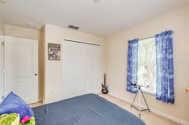 bedroom with light carpet, baseboards, visible vents, and a closet