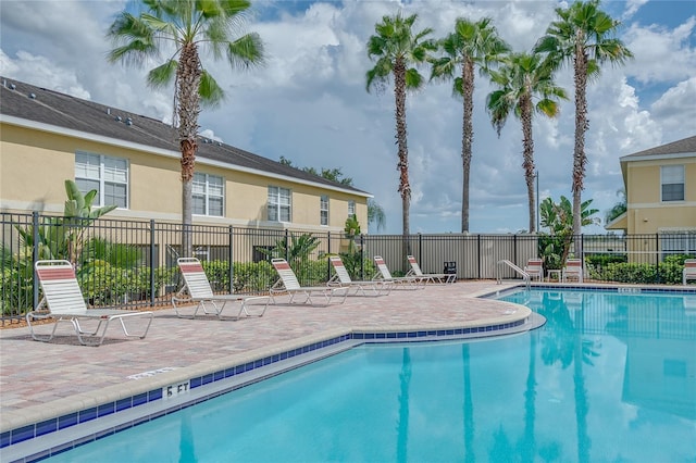 community pool with a patio area and fence