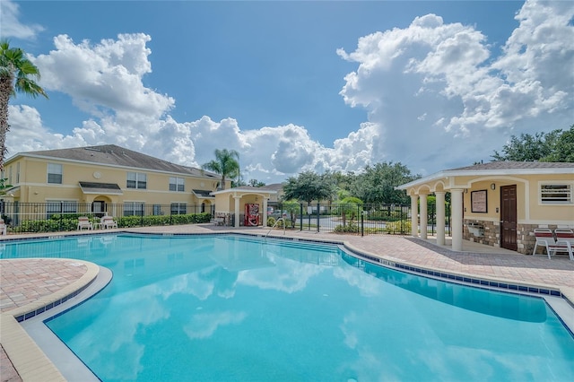 pool with a patio area and fence