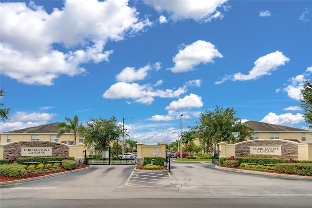 view of road featuring street lights, a gate, a gated entry, a residential view, and curbs