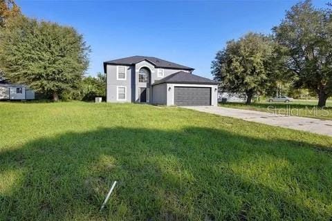 raised ranch with a garage, driveway, and a front lawn