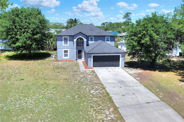 traditional-style home with a garage, concrete driveway, a shingled roof, a front yard, and stucco siding