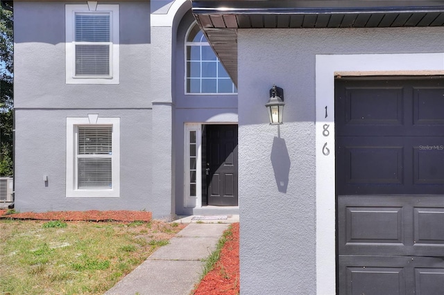 view of exterior entry featuring a garage and stucco siding