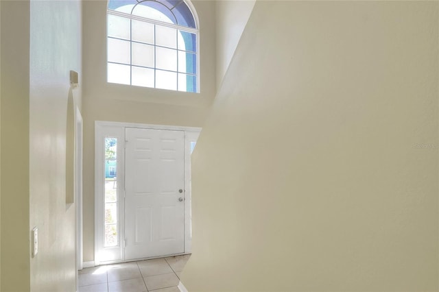 foyer entrance featuring baseboards, a high ceiling, and light tile patterned floors