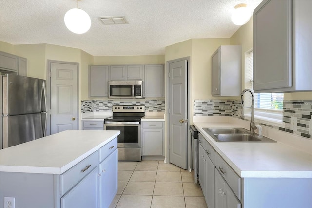 kitchen with appliances with stainless steel finishes, gray cabinetry, a sink, and visible vents