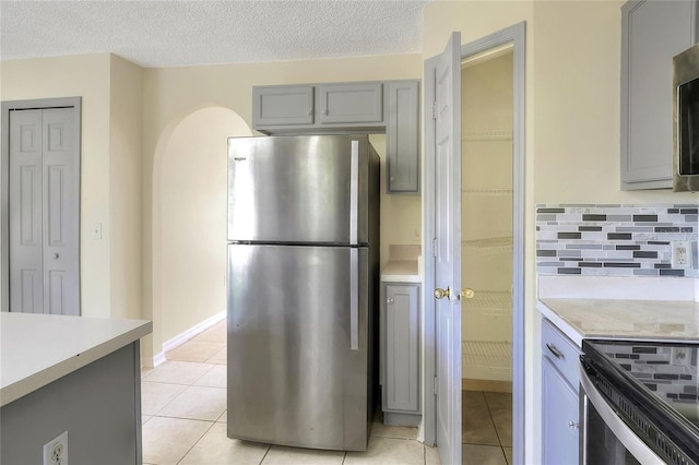 kitchen with light countertops, freestanding refrigerator, gray cabinets, and light tile patterned flooring