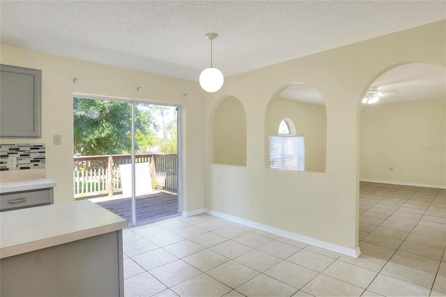 unfurnished dining area with baseboards, a textured ceiling, and light tile patterned floors