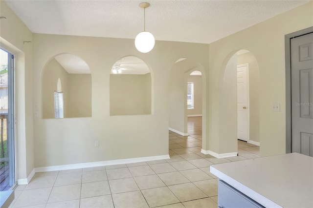 unfurnished dining area with a wealth of natural light, a textured ceiling, and light tile patterned flooring