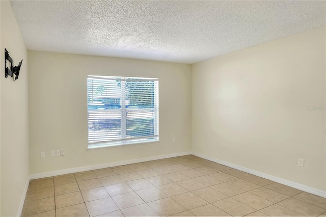 unfurnished room featuring baseboards, a textured ceiling, and light tile patterned flooring
