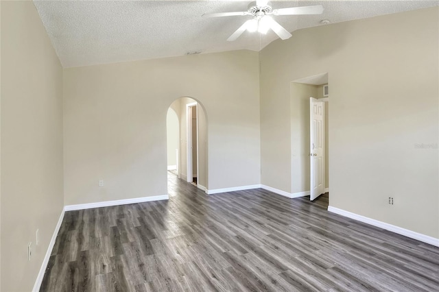 spare room with lofted ceiling, wood finished floors, a ceiling fan, arched walkways, and a textured ceiling