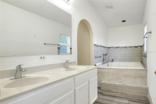 full bathroom featuring a garden tub, wood finished floors, a sink, and visible vents