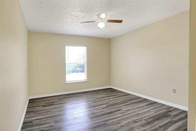 empty room with a ceiling fan, baseboards, a textured ceiling, and dark wood-type flooring