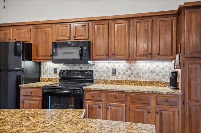 kitchen featuring light stone countertops, black appliances, and tasteful backsplash