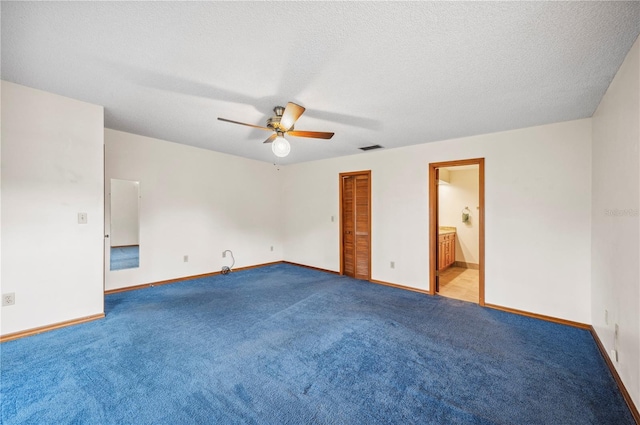 unfurnished bedroom featuring ensuite bathroom, a textured ceiling, ceiling fan, and light colored carpet