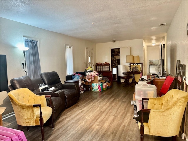 living room with visible vents, a textured ceiling, and wood finished floors