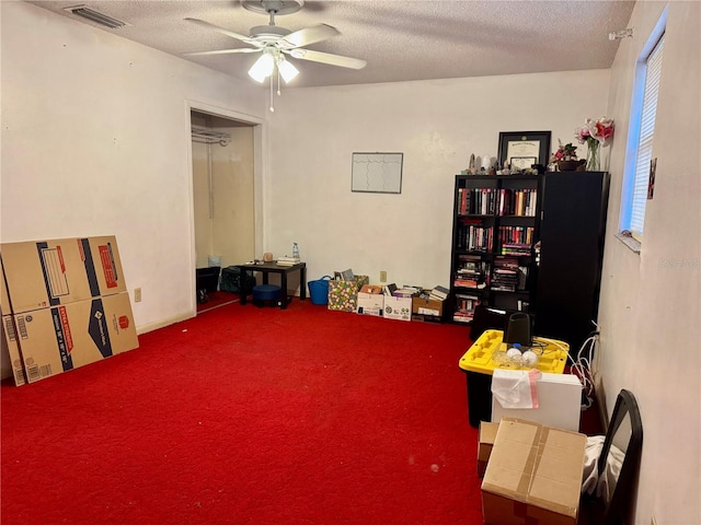 misc room with plenty of natural light, ceiling fan, carpet flooring, and a textured ceiling