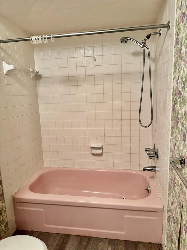 bathroom featuring toilet and tiled shower / bath