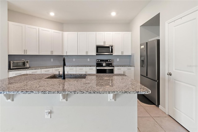 kitchen with white cabinets, a breakfast bar area, stainless steel appliances, and a sink