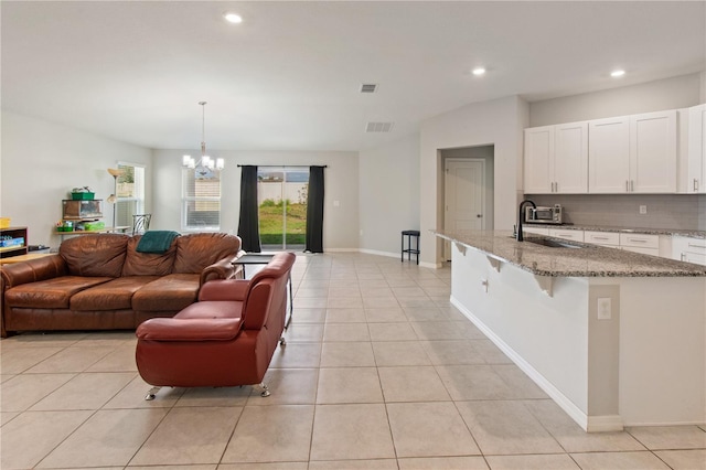 living room featuring baseboards, light tile patterned flooring, visible vents, and an inviting chandelier