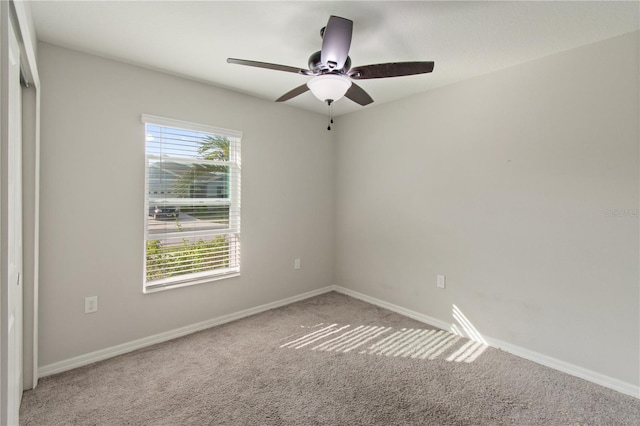 carpeted spare room featuring a ceiling fan and baseboards