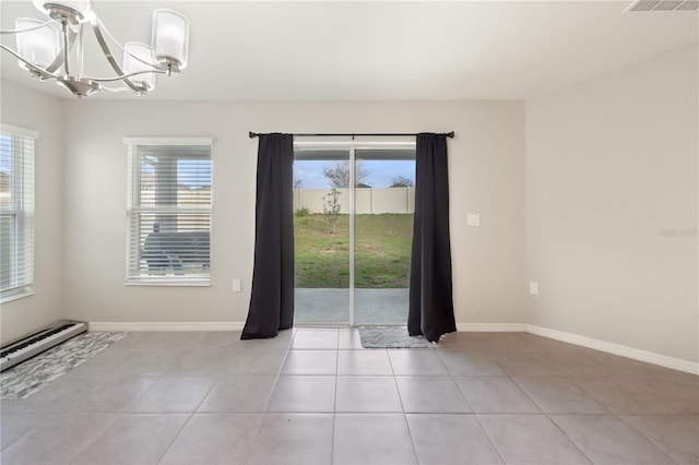 empty room with a baseboard heating unit, a healthy amount of sunlight, baseboards, and an inviting chandelier