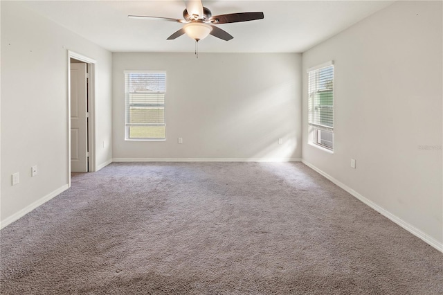 carpeted spare room featuring ceiling fan, baseboards, and a wealth of natural light