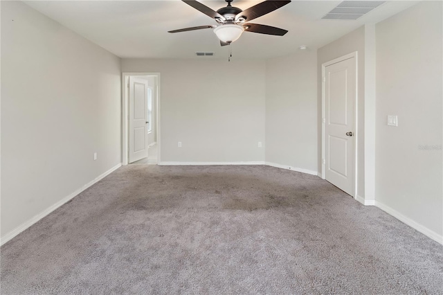 carpeted spare room with baseboards, visible vents, and ceiling fan