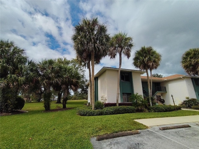 view of front of property with uncovered parking, a front lawn, and stucco siding