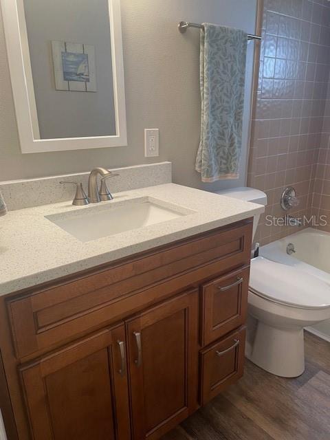 bathroom with shower / bathtub combination, vanity, wood finished floors, and toilet