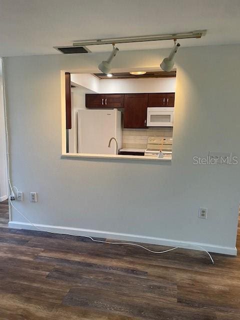 kitchen with white appliances, backsplash, dark wood finished floors, and baseboards