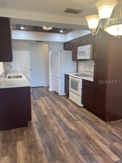 kitchen with white appliances, visible vents, light countertops, and a sink