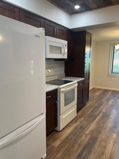 kitchen featuring white appliances, light countertops, dark wood finished floors, and dark brown cabinets