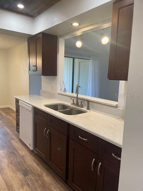 kitchen with dark brown cabinetry, dark wood finished floors, dishwasher, light countertops, and a sink