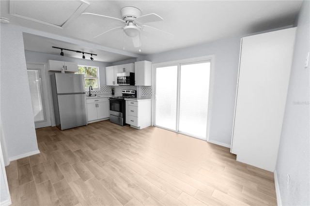 kitchen with appliances with stainless steel finishes, sink, light hardwood / wood-style flooring, white cabinets, and decorative backsplash