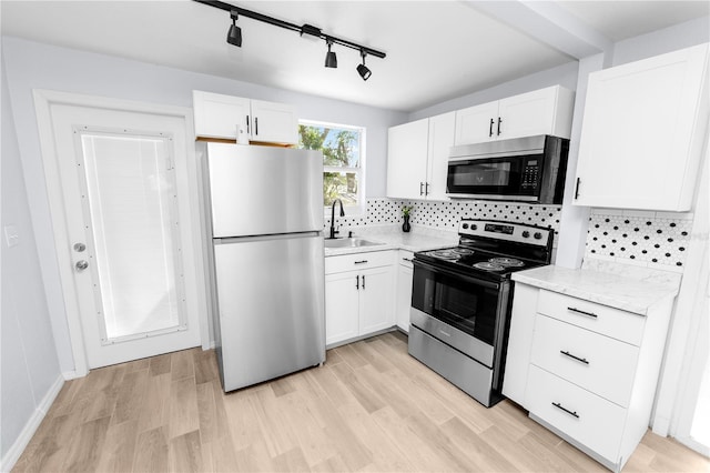 kitchen featuring appliances with stainless steel finishes, light hardwood / wood-style flooring, sink, and white cabinetry