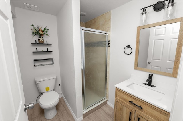 bathroom with hardwood / wood-style floors, vanity, a shower with shower door, and toilet