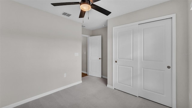 unfurnished bedroom with ceiling fan, light carpet, and a closet