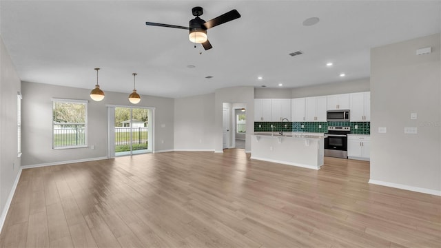 unfurnished living room with sink, ceiling fan, and light hardwood / wood-style flooring