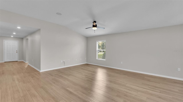 spare room featuring light hardwood / wood-style floors, vaulted ceiling, and ceiling fan